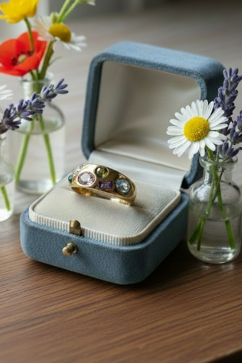 Ring in dusty blue box on warm brown wooden table with wildflowers